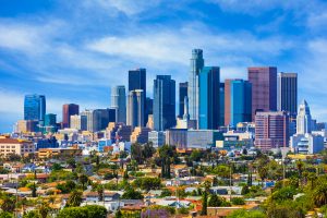Los Angeles skyline with downtown skyscrapers and surrounding neighborhoods under a blue sky.